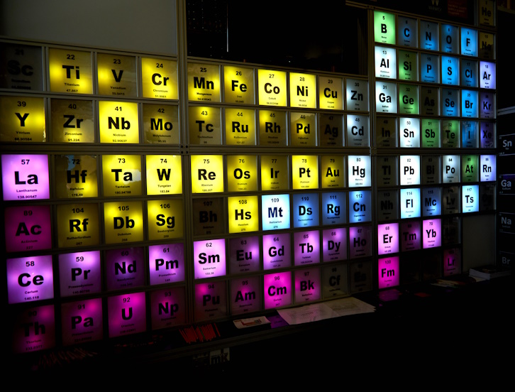 A lit-up periodic table glows in a darkened room