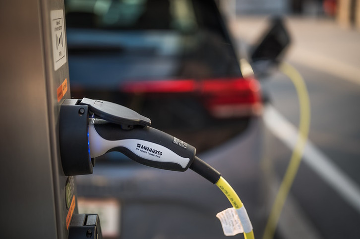 Close up of charge point of electric vehicle with car out of focus in the background