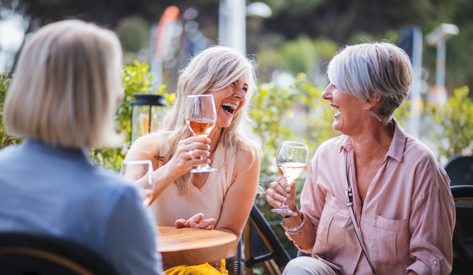 A group of women laughing over drinks